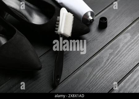 Schuhe, Bürste und schuhpolitur auf schwarzem Holzhintergrund, Nahaufnahme Stockfoto