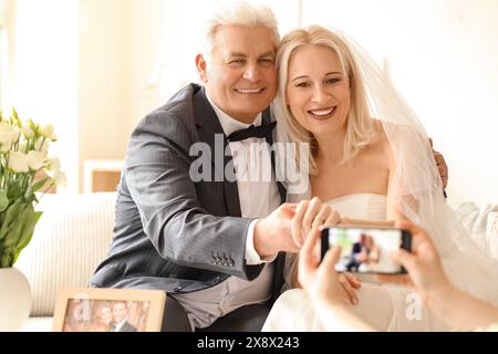 Ein reifes Paar, das zu Hause zu ihrem Hochzeitstag fotografiert wird Stockfoto