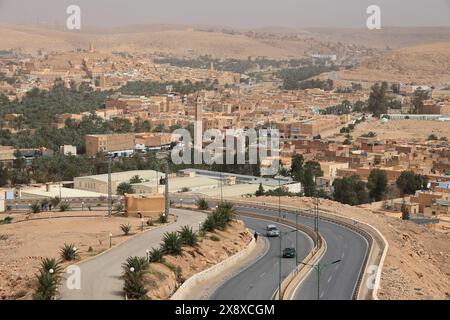 Trans-Sahar Highway N1 mit der Stadt Sidi Abaz und Ksar Bounoura im Hintergrund. Mzab-Tal. Provinz Ghardaia. Algerien Stockfoto