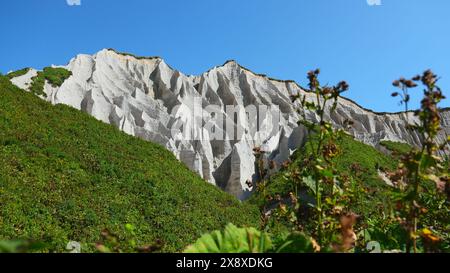 Erstaunliche weiße Berge mit grünem Gras. Clip. Wunderschöne Muster auf felsigen weißen Bergen mit hellem Grün an sonnigen Sommertagen. Weiße Steine von Stockfoto