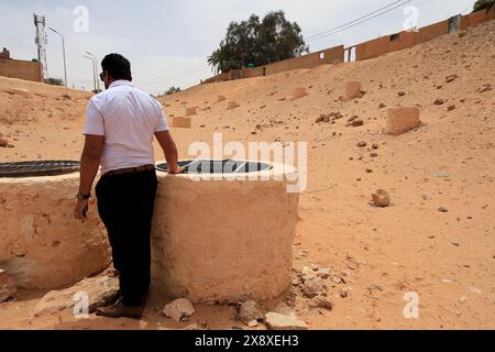 Ein Mann, der die Brunnen eines unterirdischen Wasserreservoirs des traditionellen Hochwasserverteilungs- und -Managementsystems in Ghardaia betrachtet. Mzab-Tal. Ghardaia Province.north Sahara. Algerien Stockfoto