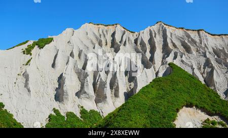 Erstaunliche weiße Berge mit grünem Gras. Clip. Wunderschöne Muster auf felsigen weißen Bergen mit hellem Grün an sonnigen Sommertagen. Weiße Steine von Stockfoto