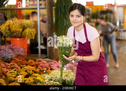 Porträt einer positiven Blumenmarktverkäuferin mit Gänseblümchen für Käufer Stockfoto
