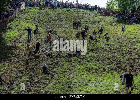 Gloucester, Großbritannien. Mai 2024. Die Teilnehmer stürzen sich auf den steilen Hügel, um in Gloucester den Boden zu erreichen. Das Gloucester Cheese Rolling Race ist ein traditioneller Wettbewerb auf dem Copper's Hill in Brockworth bei Gloucester, Großbritannien. Es zieht Menschen aus aller Welt an, an dem Rennen teilzunehmen. Die Teilnehmer jagen einen 3 kg schweren Double Gloucester Käse auf einem 200 Meter langen und über 45 Grad steilen Hügel. (Foto: Krisztian Elek/SOPA Images/SIPA USA) Credit: SIPA USA/Alamy Live News Stockfoto