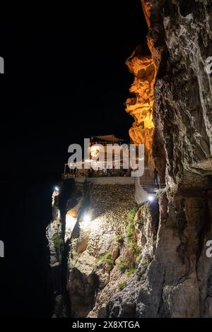 Nächtlicher Blick auf die Terrassen in der Mitte der Klippe vor dem Meer der Cova d'en Xoroi bei Nacht, berühmte Diskothek auf der Insel Stockfoto