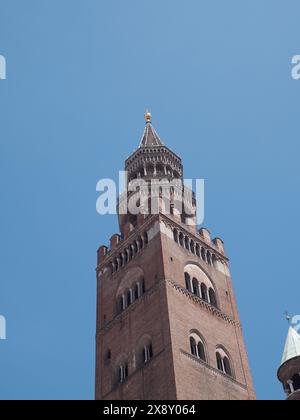 Cremona, Italien - 15. Mai 2024 der atemberaubende mittelalterliche Backsteinturm steht hoch und zeigt komplexe architektonische Details vor einem leuchtend blauen Himmel Stockfoto