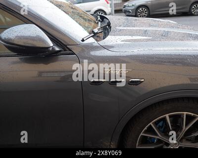 Cremona, Italien - 15. Mai 2024 Großaufnahme eines eleganten, luxuriösen Maserati suv Grecale Trofeo Seitenverkleidung und Rad, glitzernd von Regentropfen unter bewölktem Himmel Stockfoto