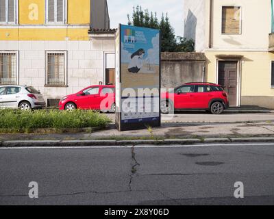 Cremona, Italien - 15. Mai 2024 Straßenansicht mit einer Werbetafel für ein lokales Kunstfestival mit pulsierenden Parkwagen und Wohngebäuden Stockfoto