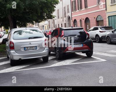 Cremona, Italien - 15. Mai 2024 Roter kompakter Toyota Aigo Crossovrt suv, der neben einer Zebrakreuzung auf einer städtischen Straße geparkt ist, mit Gebäuden und Autos in der Th Stockfoto