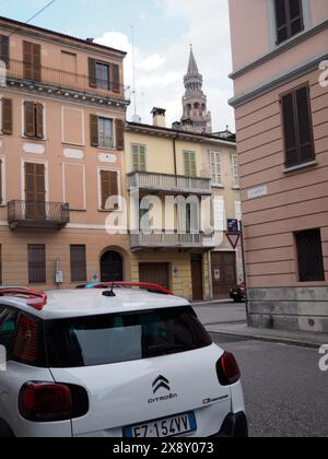 Cremona, Italien - 15. Mai 2024 malerische italienische Straße mit traditionellen Gebäuden und einem modernen Auto, das im Vordergrund unter einem klaren blauen geparkt ist Stockfoto