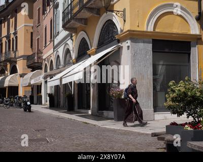 Cremona, Italien - 15. Mai 2024 einsamer Mönch in traditionellen Gewändern spaziert an Boutiquen in einer malerischen europäischen Straße mit lebhafter Architektur vorbei Stockfoto