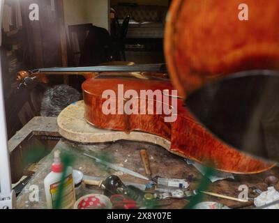 Cremona, Italien - 15. Mai 2024 Nahaufnahme einer Geige auf einem überdachten Werkstatttisch, umgeben von Werkzeugen und Materialien, die die handwerkliche Arbeit in der Musica hervorheben Stockfoto