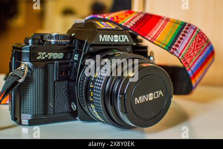 Nahaufnahme einer klassischen Minolta X-700 Filmkamera mit einem bunten Riemen. Ideal für Liebhaber von Vintage-Kameras, Filmfotografie und Sammler. Stockfoto