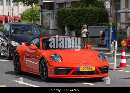 Luxemburg-Stadt, Luxemburg - Blick auf einen orangen Porsche 992 Carrera 4S Cabriolet auf einer Straße. Stockfoto