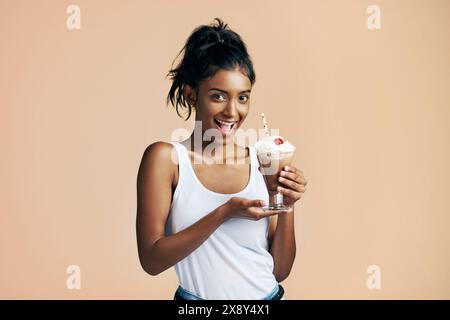 Aufgeregt, Milchshake und Porträt des glücklichen indischen Mädchens im Studio auf braunem Hintergrund zum Dessert. Getränk, Schokolade und Getränk im Glas mit einem Lächeln von Stockfoto