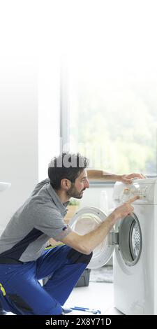 Der Servicetechniker repariert eine Waschmaschine, verwendet das Bedienfeld und überprüft die Einstellungen Stockfoto