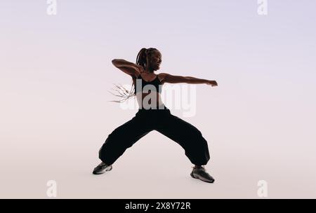 Eine Tänzerin zeigt energiegeladene Tanzbewegungen in einem Studio. Mit ausdrucksstarken Körperbewegungen strahlt sie Fitness und Flexibilität aus. Lustig und lebhaft, sie captain Stockfoto