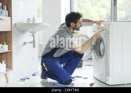 Der Servicetechniker repariert eine Waschmaschine, verwendet das Bedienfeld und überprüft die Einstellungen Stockfoto