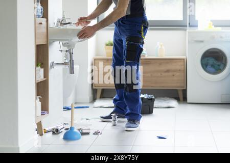 Ein professioneller Klempner repariert einen Wasserhahn im Badezimmer Stockfoto