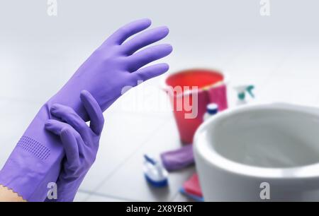 Weibliche Hände tragen Schutzhandschuhe und Toilette im Hintergrund Stockfoto