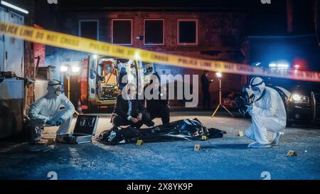 Polizistin und Ermittler arbeiten als Team an der Lösung eines Mordfalls am Tatort. Professionelles Ermittlungsteam, das Muster in den Beweisen durchsucht, um den Fall zu brechen Stockfoto