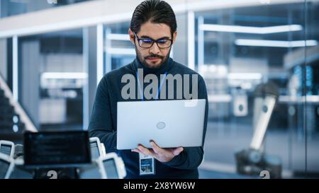 Hübscher hispanischer Mann mit Brille, lächelnd und in die Kamera schaut. Junger intelligenter, multiethnischer Ingenieur, Entwickler oder Wissenschaftler, der im Büro für Entwicklungstechnologie arbeitet. Stockfoto