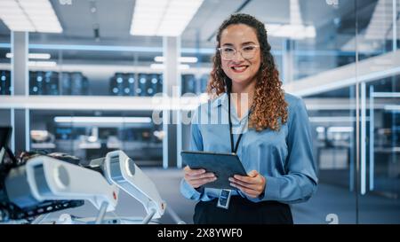 Porträt einer schönen hispanischen Frau, die Brille trägt, einen Tablet-Computer benutzt, die Kamera ansieht und lächelt. Geschäftsfrau, It-Managerin, Robotik-Ingenieurin. Stockfoto