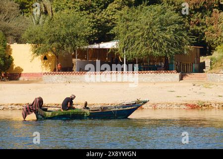 Fischer reparieren Fischernetze in seinem Boot am Ufer des Nils in Assuan, Ägypten Stockfoto