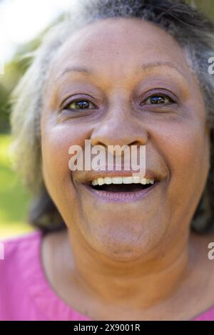 Draußen, zweirassige Seniorin in rosa Hemd, lächelnd Stockfoto