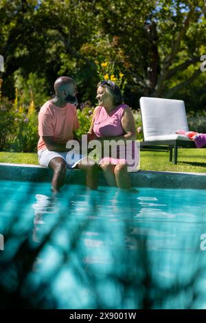 Im Freien halten sich verschiedene Seniorenfreunde am Pool und unterhalten sich glücklich Stockfoto