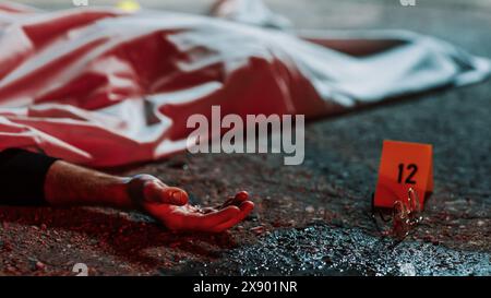 Close Up Low Angle: Eine Leiche mit einer blutigen Hand, die auf dem Boden liegt und bedeckt ist. Grausamer Mordfall, der das Opfer zum Tode lässt. Brille und Blut sind als Beweis neben der Leiche markiert. Kinoaufnahme Stockfoto