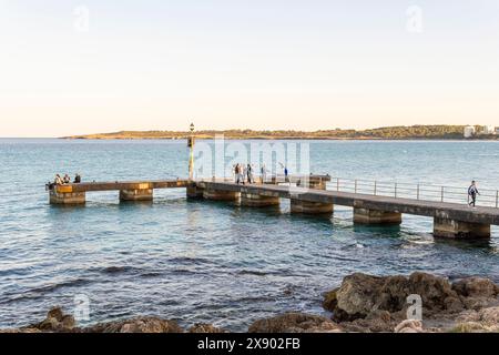 Cala Millor, Spanien; 13. april 2024: Allgemeiner Blick auf den alten Pier mit Touristen im mallorquinischen Ferienort Cala Millor bei Sonnenuntergang Stockfoto