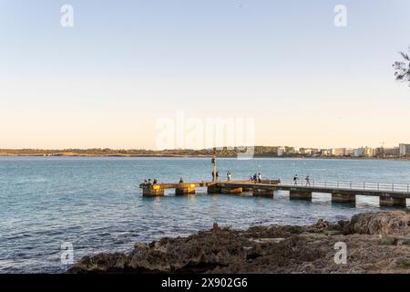 Cala Millor, Spanien; 13. april 2024: Allgemeiner Blick auf den alten Pier mit Touristen im mallorquinischen Ferienort Cala Millor bei Sonnenuntergang Stockfoto