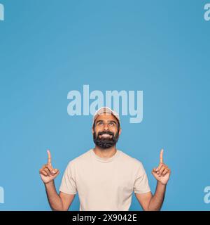 Lächelnder Mann Mit Beigem Hemd, Der Vor Blauem Hintergrund Zeigt Stockfoto