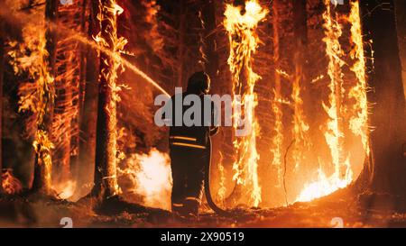 Ein erfahrener Feuerwehrmann löscht ein Wildlandfeuer tief in den Wäldern. Profi in Sicherheitsuniform und Helm, der Wasser sprüht, um große Flammen zu bekämpfen, die sich durch Bäume ausbreiten. Stockfoto