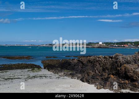 Blick über Fort Grey in der Rocquaine Bay von der felsigen Küste von Pleinmont an einem schönen sonnigen Maitag mit blauem Meer und Himmel im Südwesten Guernsey Stockfoto