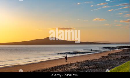 Vor dem Hintergrund von Rangitoto Island trainieren die Menschen am Campbells Bay Beach an der Ostküste der Nordinsel in der Nähe von Auckland, Neuseeland Stockfoto