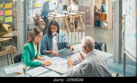 Vielfältige Gruppe von Personen, die sich in einem zwanglosen, modernen Konferenzraum im Büro mit einem Laptop unterhalten. Gruppe von Kollegen aus verschiedenen ethnischen Gruppen, die als Team für Krisenmanagement arbeiten. Stockfoto