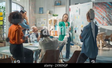 Die schöne schwarze Geschäftsfrau gibt ihren Geschäftskollegen im Konferenzraum Bericht, eine Präsentation und zeigt Grafiken, Tortendiagramme und das Wachstum von Unternehmen auf einem Whiteboard Stockfoto
