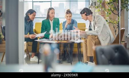 Vielfältige Gruppe von Personen, die sich in einem zwanglosen, modernen Konferenzraum im Büro mit einem Laptop unterhalten. Gruppe von Kollegen aus verschiedenen ethnischen Gruppen, die als Team für Krisenmanagement arbeiten. Stockfoto