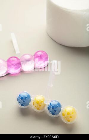 Toilettenkugeln und Toilettenpapier auf grauem Hintergrund. Reinigen Sie die Toilettenschüssel mit Reinigungs- und Erfrischungsbällchen. Leerzeichen für Text Stockfoto