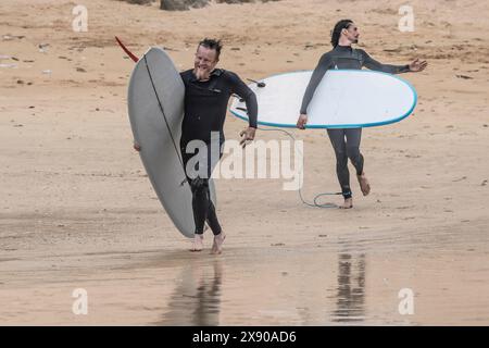 Surfer, die zum Meer laufen, treten beim Sand Bandit Showdown Surfing Competition am GT Western Great Western Beach in Newquay in Cornwall an Stockfoto