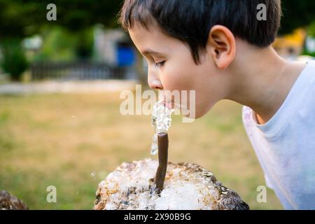 Kinder trinken Wasser aus einem Brunnen im Park Stockfoto