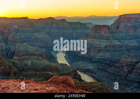 Atemberaubende Aussicht auf den sich windenden Fluss des Grand Canyon, wunderschön beleuchtet von den goldenen Strahlen der untergehenden Sonne. Stockfoto