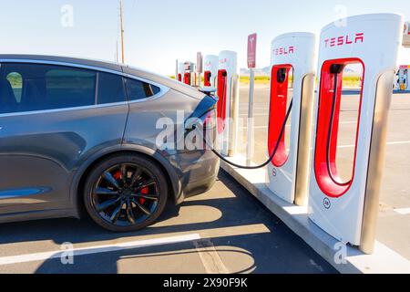 White Hills, Arizona – 14. April 2024: Tesla Model X wurde an eine Supercharger-Station mit mehreren Ladeeinheiten mit dem Tesla-Logo im V angeschlossen Stockfoto