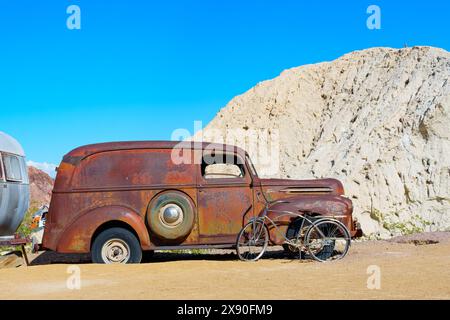 Nelson, Nevada - 15. April 2024: Rostiger Oldtimer mit Wohnmobil und Fahrrad in der Wüste Stockfoto