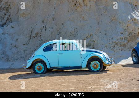 Nelson, Nevada - 15. April 2024: Der Volkswagen Beetle in Vintage-Blau parkt in der Wüste neben einem Felsvorsprung in Nelson Ghost Town Stockfoto