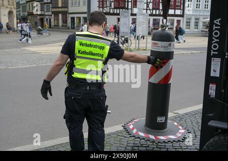 Erfurt, Deutschland. Mai 2024. Ein Mitglied des katholischen Tages-Verkehrsteams transportiert eine Barrieresäule über den Domplatz. Die Aufbauarbeiten für den Katholikentag in der Erfurter Innenstadt sind in vollem Gange. Quelle: Heiko Rebsch/dpa/Alamy Live News Stockfoto