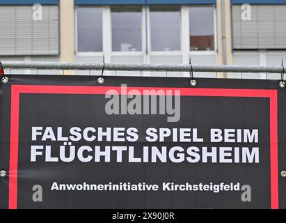 28. Mai 2024, Brandenburg, Potsdam: Ein Banner einer Bürgerinitiative gegen ein geplantes Flüchtlingsheim hängt an einem Bauzaun. Widerstand gegen geplante Unterkünfte für Flüchtlinge am Stadtrand Potsdams. Ein Nachbar hat einen dringenden Antrag beim Verwaltungsgericht Potsdam gestellt, wie ein Sprecher der Behörde am Dienstag mitteilte. Der Antrag richtet sich gegen die Genehmigung zur Umnutzung des ehemals gewerblich genutzten Gebäudes. Mit dem Dringlichkeitsantrag soll das Projekt gestoppt werden, bis eine rechtskräftige Entscheidung getroffen ist. Foto: Patrick Pleul/dpa Stockfoto