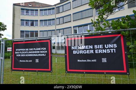 28. Mai 2024, Brandenburg, Potsdam: Banner einer Bürgerinitiative gegen ein geplantes Flüchtlingsheim hängen an einem Bauzaun. Widerstand gegen geplante Unterkünfte für Flüchtlinge am Stadtrand Potsdams. Ein Nachbar hat einen dringenden Antrag beim Verwaltungsgericht Potsdam gestellt, wie ein Sprecher der Behörde am Dienstag mitteilte. Der Antrag richtet sich gegen die Genehmigung zur Umnutzung des ehemals gewerblich genutzten Gebäudes. Mit dem Dringlichkeitsantrag soll das Projekt gestoppt werden, bis eine rechtskräftige Entscheidung getroffen ist. Foto: Patrick Pleul/dpa Stockfoto